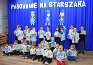 Dzieci ustawione na tle dekoracji, pozują do pamiątkowej fotografii